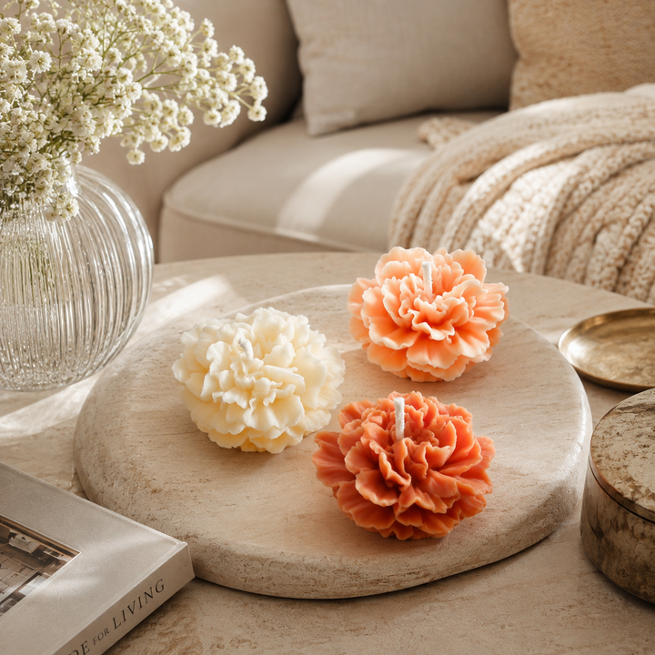 Trois bougies Little pivoine en forme de fleurs disposées sur une table dans un salon lumineux