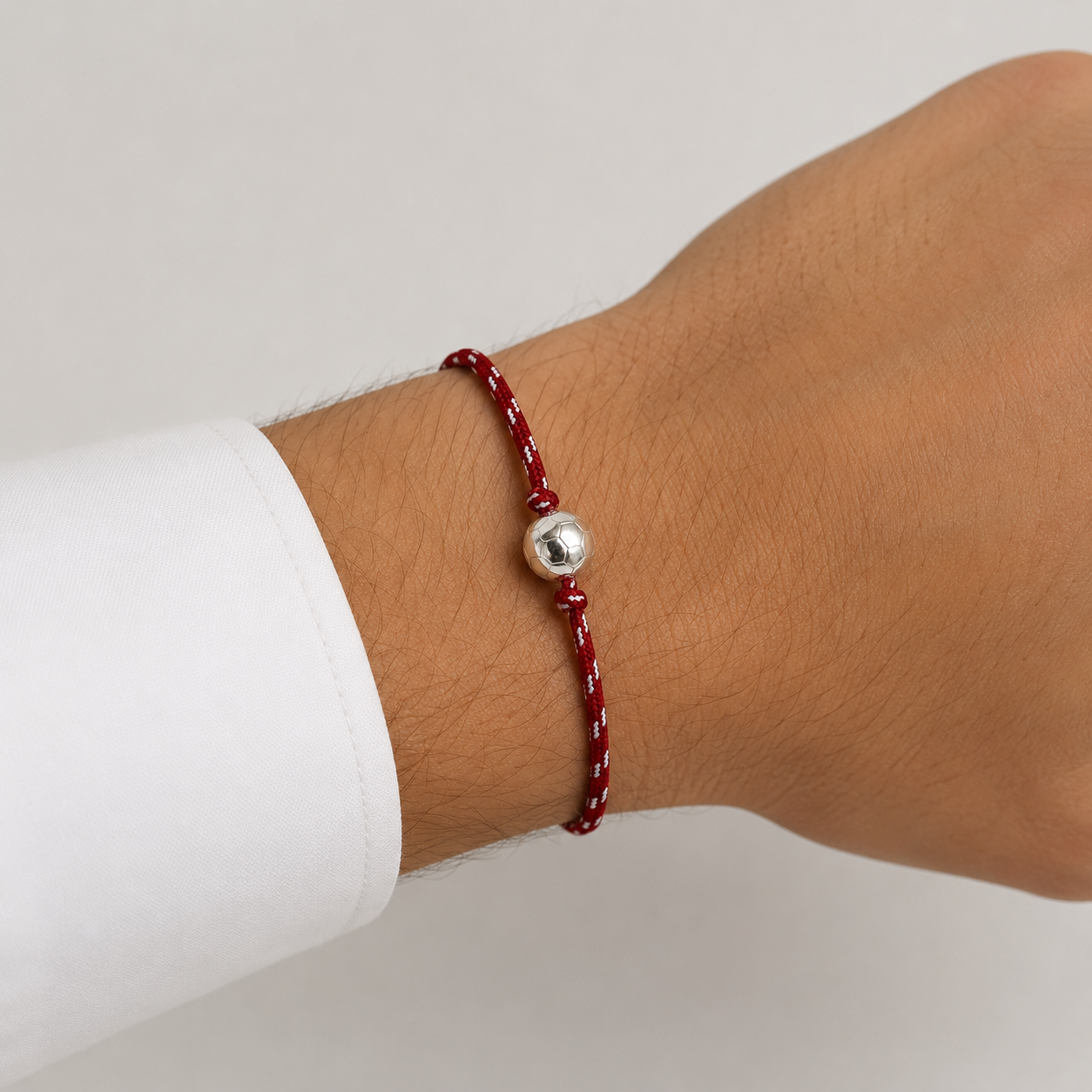 Bracelet football rouge et blanc avec ballon argenté porté au poignet d’un homme